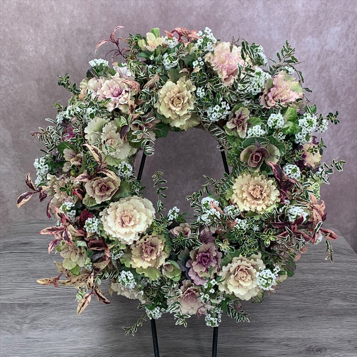 花創人のオーダーメイド寄せ植えで制作した、フリルがかわいい葉牡丹リースのプランツギャザリング作品。はぼたんクラシカルボンボン、はぼたんセッションシリーズ ベナ、スイートアリッサム、ロニセラ ホワイトマジック、西洋イワナンテン メルベイユを使い、冬の玄関やウェルカムフラワー、開店祝い、新築祝い、全国発送のギャザリングオーダーにおすすめのリース寄せ植えです。