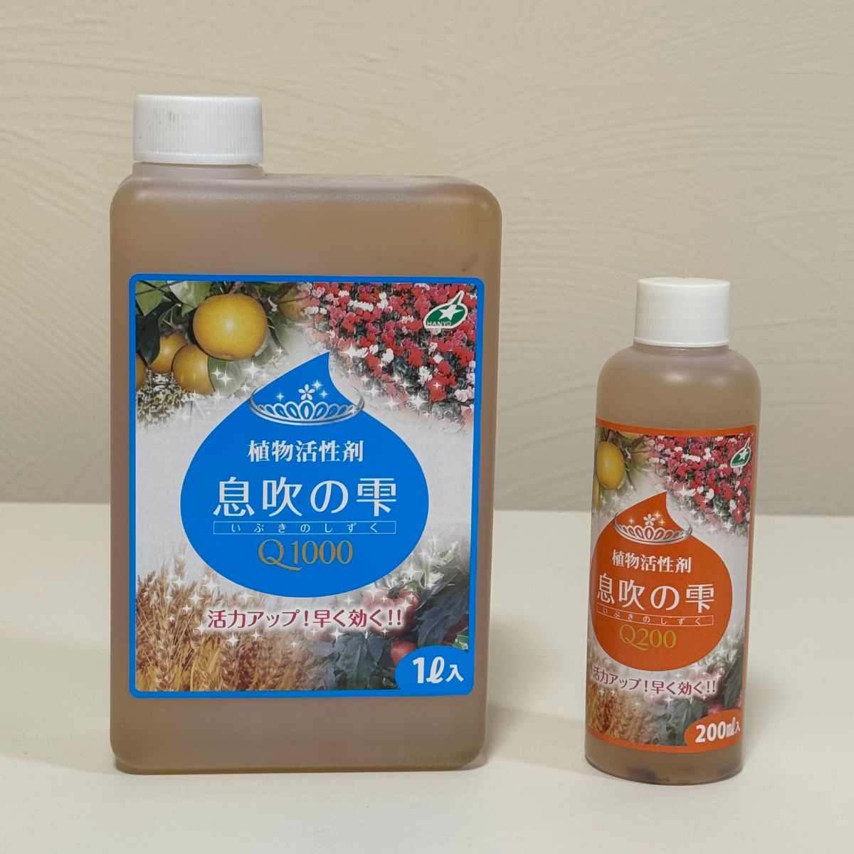 花創人で販売する植物活性剤「息吹の雫Q1000」1Lと「息吹の雫Q200」200mlを並べた容量比較。使用量や育てている植物の数に合わせてサイズを選べます。水で希釈して使用し、草花、花苗、野菜、果樹、観葉植物、多肉植物など幅広い植物に使える、花創人ガーデニング教室おすすめの植物用活力剤です。